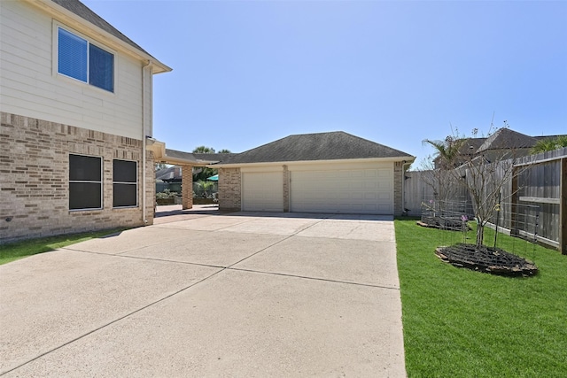 view of property exterior featuring an outbuilding, fence, concrete driveway, a lawn, and brick siding