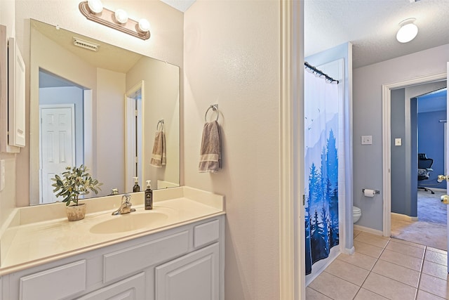 bathroom featuring visible vents, toilet, vanity, tile patterned floors, and a textured ceiling