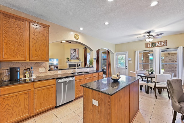 kitchen featuring ceiling fan, dishwasher, light tile patterned flooring, arched walkways, and a sink