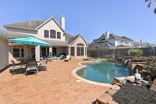 view of swimming pool with a fire pit, a pool with connected hot tub, fence, outdoor dining area, and a patio