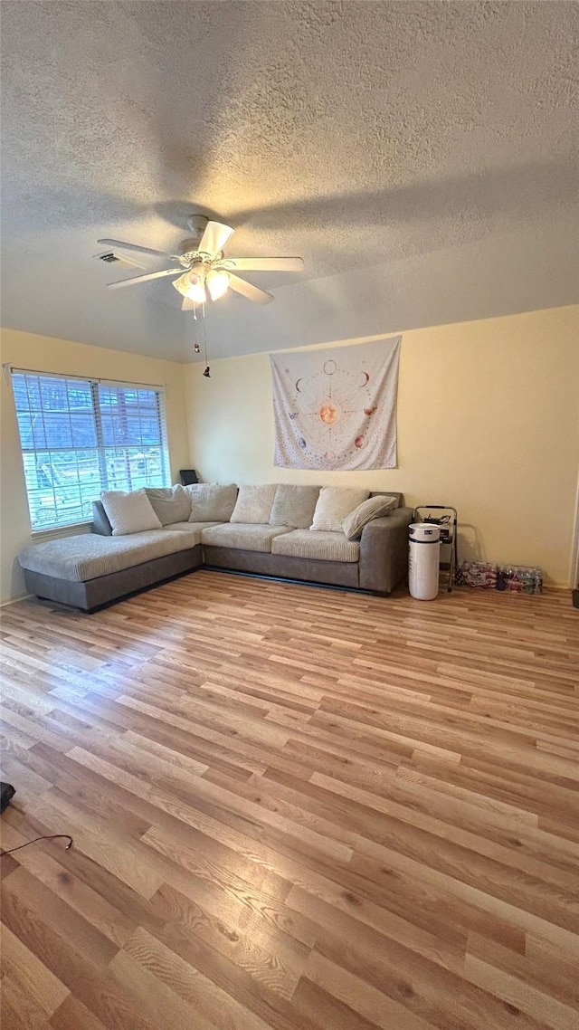 unfurnished living room featuring a textured ceiling, a ceiling fan, and wood finished floors