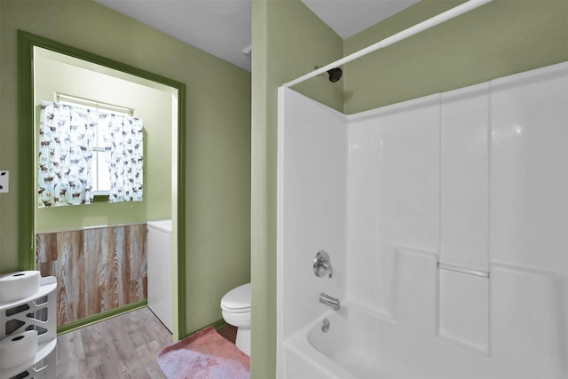 bathroom with toilet, wood finished floors, and bathing tub / shower combination