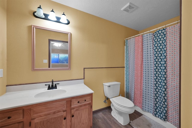 full bath with vanity, wood finished floors, visible vents, a textured ceiling, and toilet