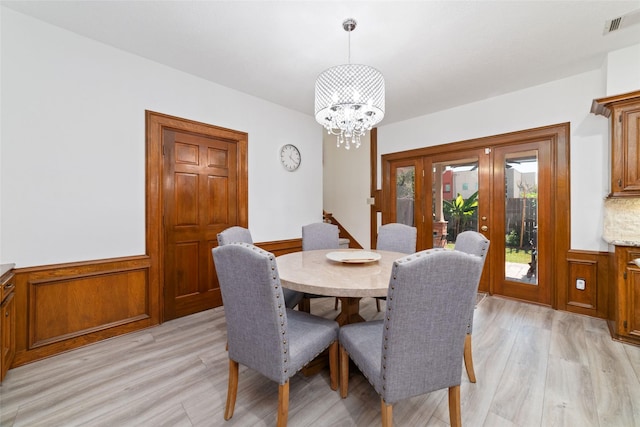 dining room with light wood-style flooring, a chandelier, and wainscoting