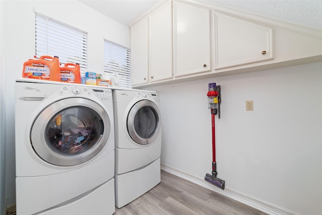 laundry room with cabinet space, washing machine and dryer, and light wood-type flooring