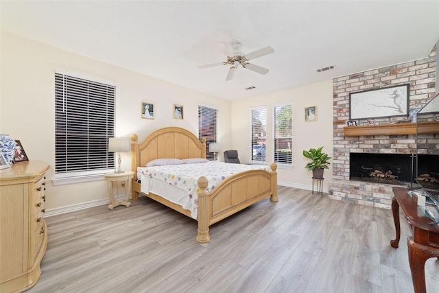 bedroom featuring a fireplace, light wood-style flooring, baseboards, and visible vents