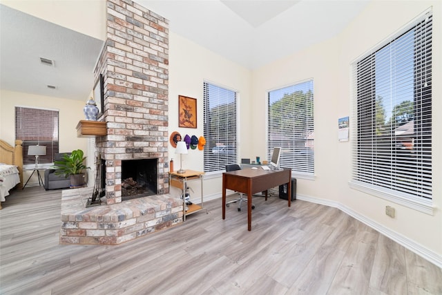 home office featuring a fireplace, baseboards, and wood finished floors