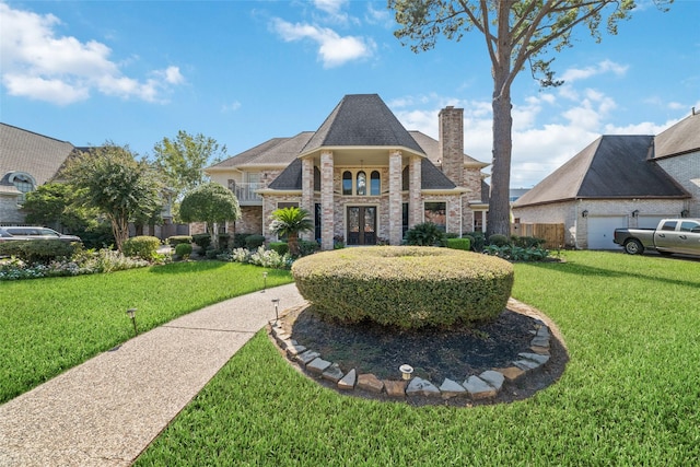 french country home with brick siding, a chimney, and a front yard