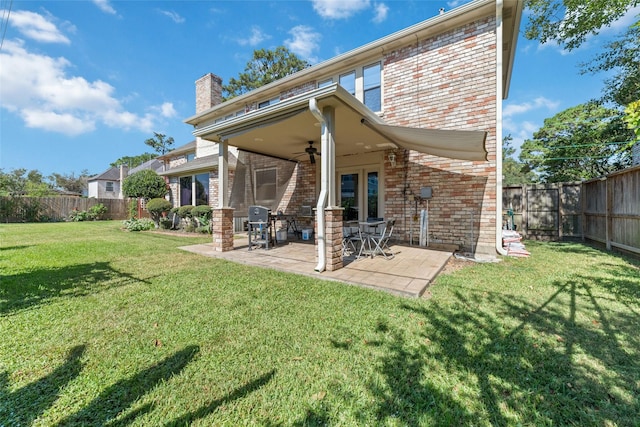 back of property with a yard, a fenced backyard, brick siding, and ceiling fan