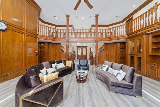 living room with crown molding, light wood-type flooring, stairs, a ceiling fan, and ornate columns