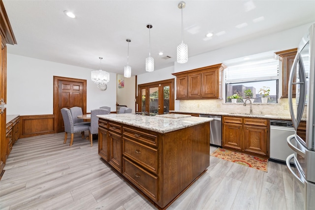 kitchen with a sink, appliances with stainless steel finishes, a wealth of natural light, and wainscoting