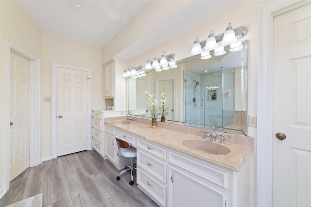 full bathroom with a sink, double vanity, wood finished floors, and a shower stall