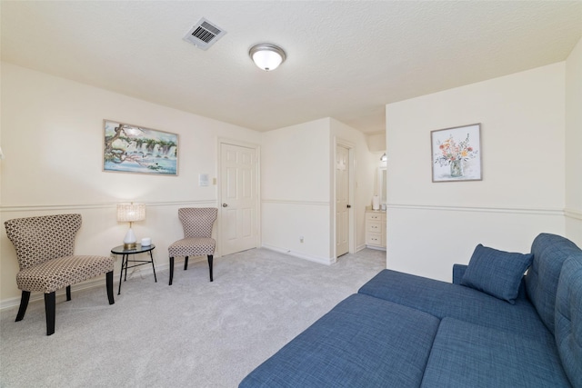 sitting room featuring visible vents, baseboards, light colored carpet, and a textured ceiling