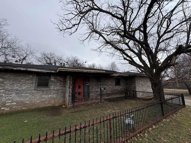 view of front of house with brick siding, a front lawn, and fence