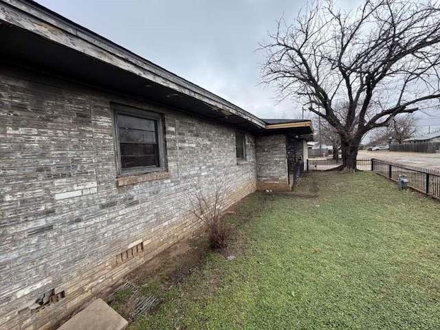 view of side of home featuring a fenced backyard, crawl space, brick siding, and a yard