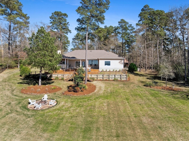 back of house with a wooden deck, a lawn, and a fire pit