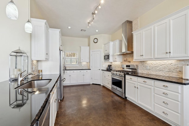 kitchen with a sink, decorative backsplash, white cabinets, appliances with stainless steel finishes, and wall chimney range hood