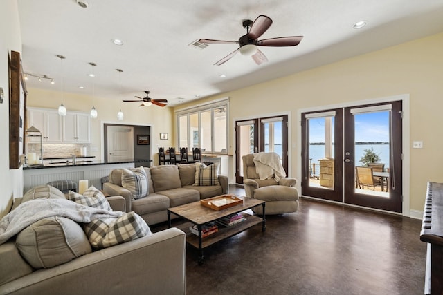 living room with a healthy amount of sunlight, french doors, concrete floors, and ceiling fan