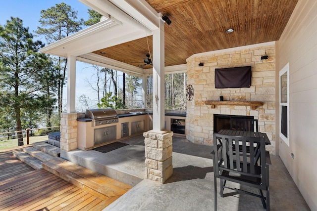 view of patio / terrace with an outdoor kitchen, grilling area, a ceiling fan, and an outdoor stone fireplace