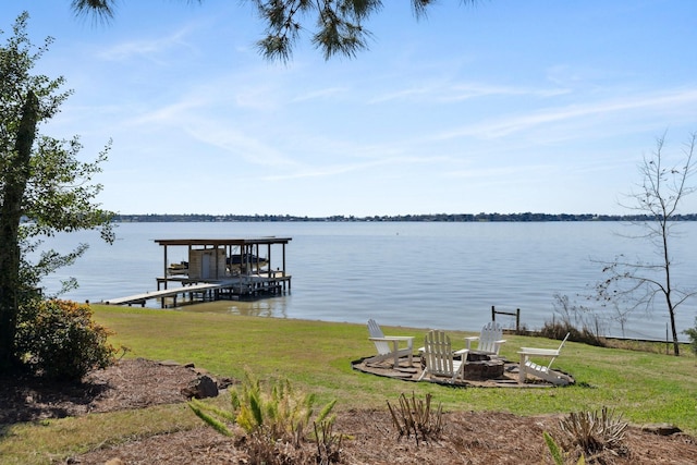 view of dock with boat lift, a water view, a lawn, and an outdoor fire pit