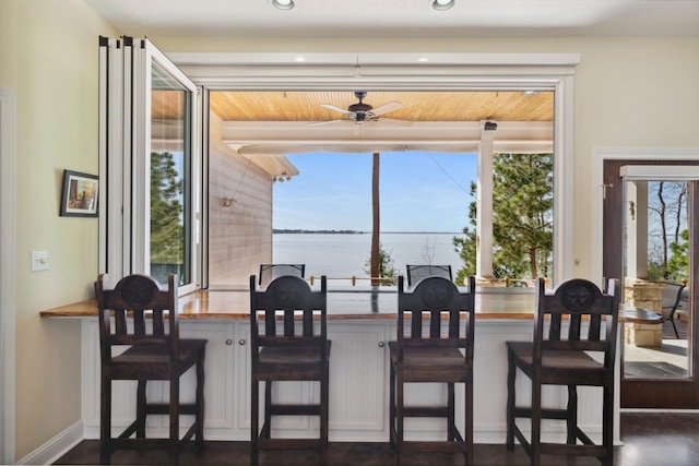 dining area featuring baseboards, a water view, and a ceiling fan