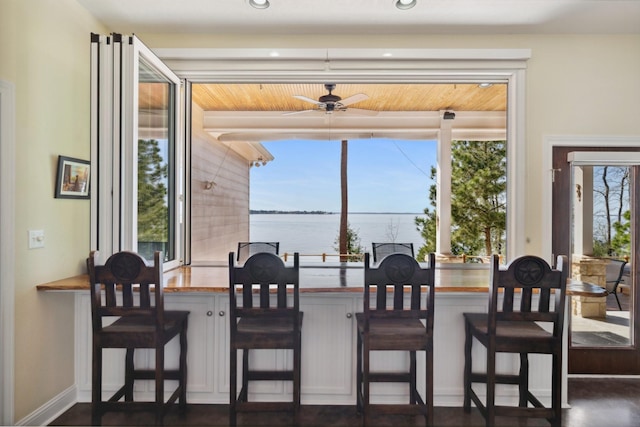 dining space with baseboards, a water view, and ceiling fan