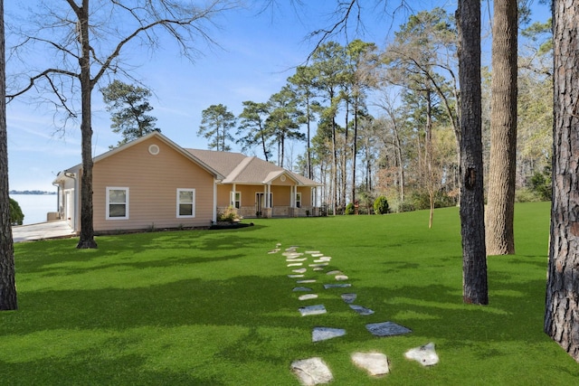 view of yard with a garage, a porch, and concrete driveway
