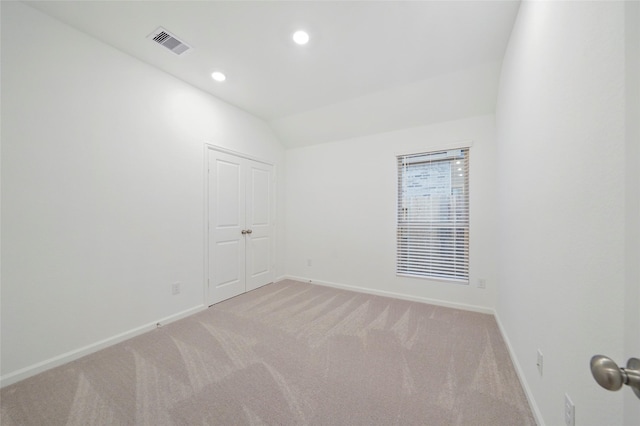 unfurnished room featuring light carpet, visible vents, baseboards, and vaulted ceiling