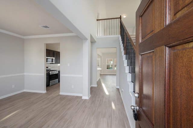 foyer with stairway, baseboards, light wood-style floors, and crown molding