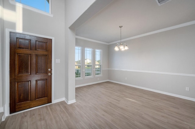 foyer entrance featuring baseboards, a notable chandelier, light wood-style flooring, and crown molding