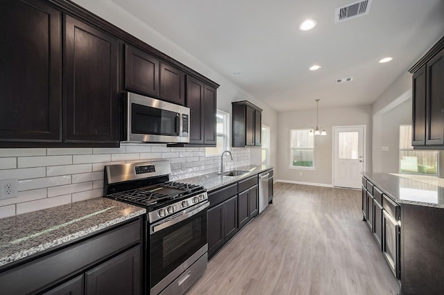 kitchen with tasteful backsplash, visible vents, stone counters, light wood-style floors, and stainless steel appliances