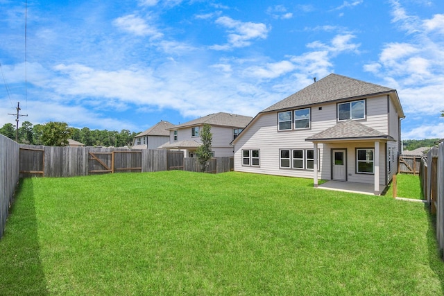 rear view of property with a yard, a patio, a fenced backyard, and a shingled roof