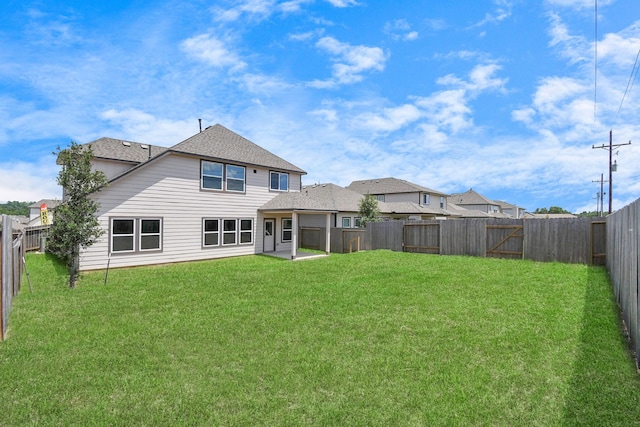 rear view of property featuring a lawn, a fenced backyard, and roof with shingles