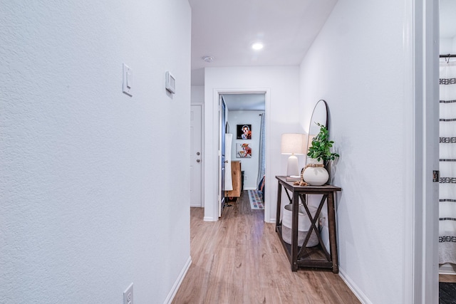 hall with light wood-type flooring and baseboards