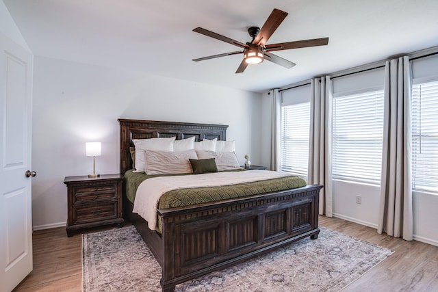 bedroom featuring baseboards, light wood finished floors, and ceiling fan