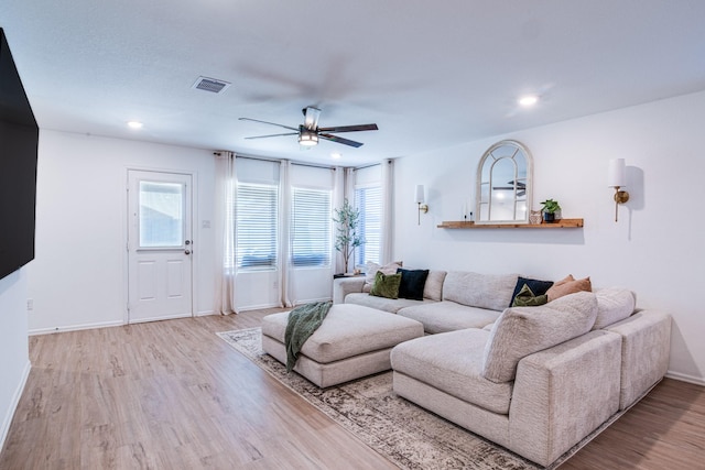 living room featuring a wealth of natural light, visible vents, ceiling fan, and wood finished floors