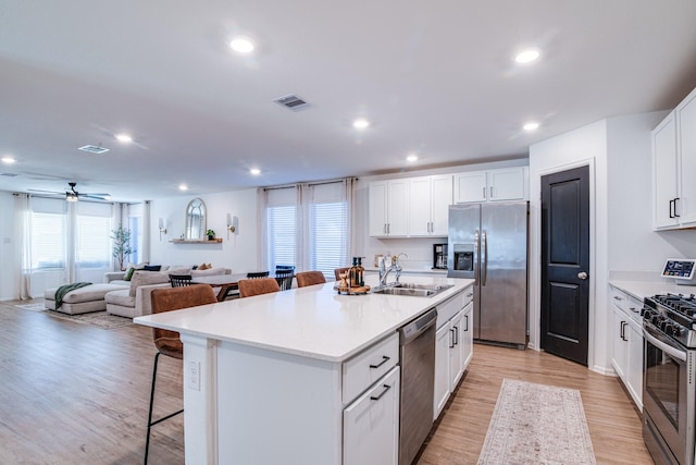 kitchen featuring visible vents, a breakfast bar, light wood-style flooring, a sink, and stainless steel appliances