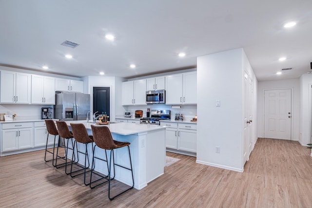 kitchen with light countertops, a breakfast bar area, light wood finished floors, and appliances with stainless steel finishes