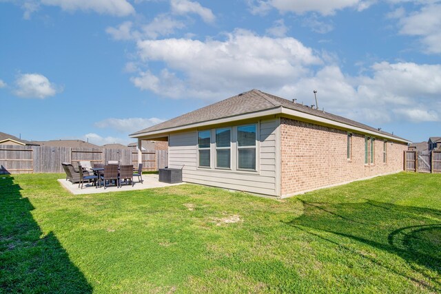 rear view of house with central AC, a fenced backyard, a yard, brick siding, and a patio area