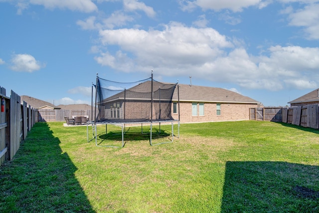 view of yard featuring a trampoline and a fenced backyard