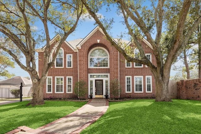 view of front of property with brick siding, a front lawn, and fence