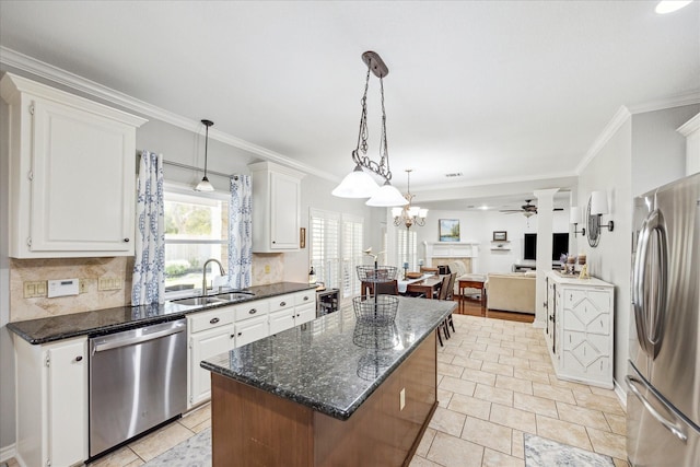 kitchen with a sink, stainless steel appliances, white cabinetry, backsplash, and a center island