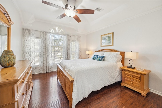 bedroom with visible vents, dark wood-type flooring, baseboards, a tray ceiling, and ornamental molding