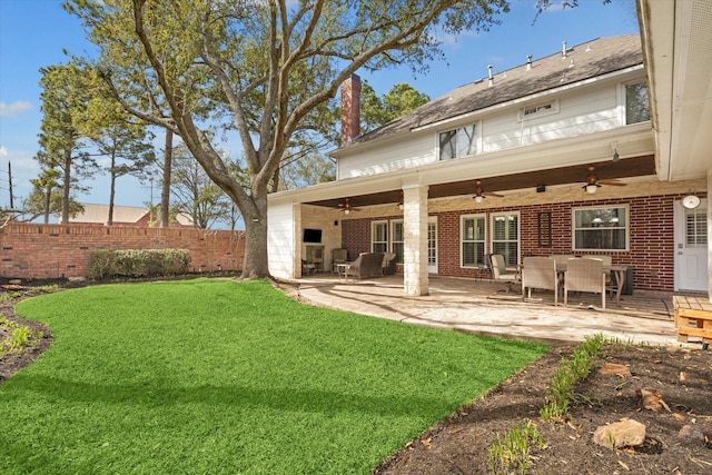 rear view of house with a lawn, a patio, fence, brick siding, and ceiling fan