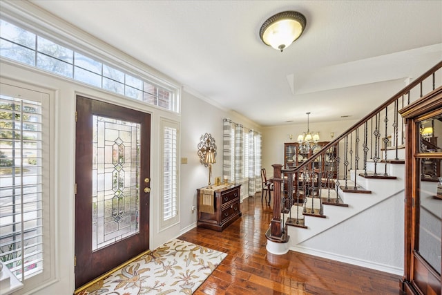 foyer featuring stairway, baseboards, an inviting chandelier, and dark wood-style flooring