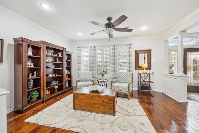 living area featuring ornate columns, hardwood / wood-style floors, ceiling fan, and ornamental molding