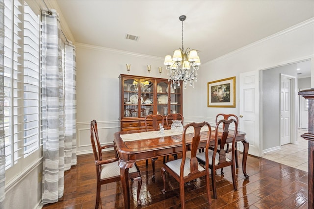 dining area with visible vents, a healthy amount of sunlight, ornamental molding, wood finished floors, and a notable chandelier