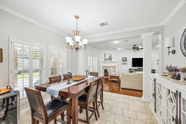 dining room featuring visible vents, ornamental molding, ceiling fan with notable chandelier, light tile patterned flooring, and a fireplace