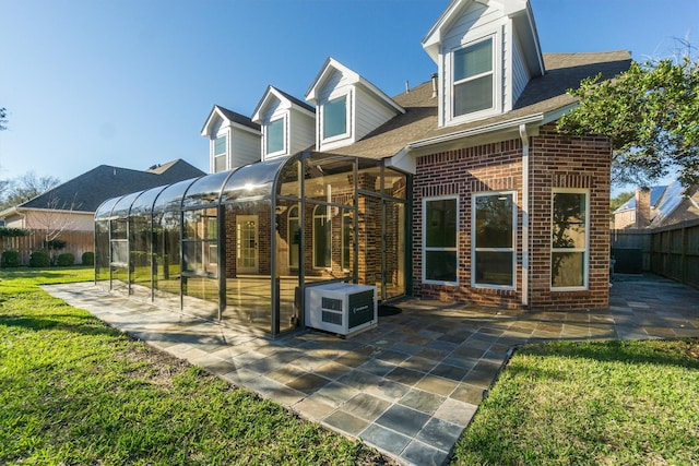 back of property with a patio area, a fenced backyard, brick siding, and a sunroom