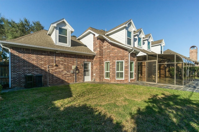 rear view of property featuring brick siding, a shingled roof, a yard, and a sunroom